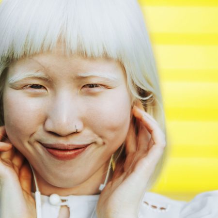 Cute albino girl listening to her favorite music through earphon